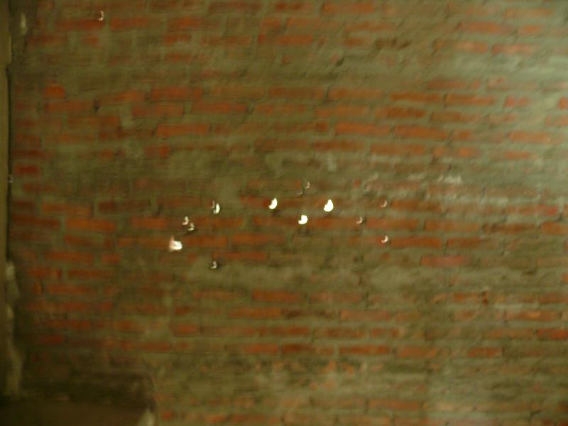 P1000275.JPG - The wall separating the master bath from the kitchen. Yes, those are spots of daylight. All will be healed once the new walls are put in place.