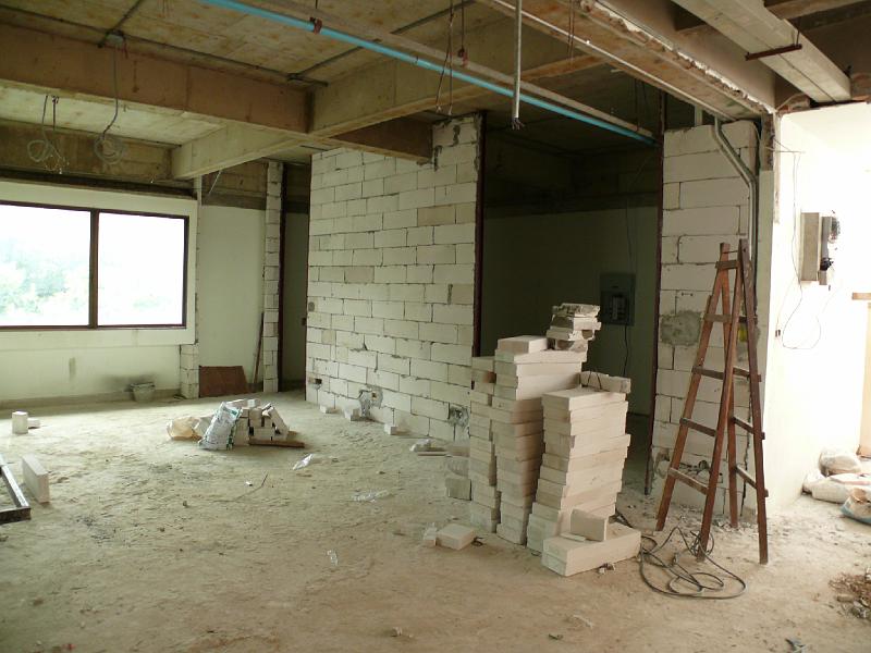 P1000295.JPG - Just to the left of the entrance, you're seeing a wall going up to define the boundary between Jon's office (the dark area in background) and the living room. The wall in the center (just to the left of the brick pile) will be the living room wall.