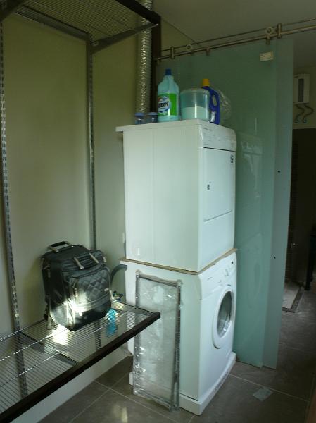 P1000814.JPG - Off of the guest room is guest shelving (again from The Container Store). And stacked washer and dryer. The chosen appliances are a good compromise. I've experienced two extremes of laundry appliances (heavy US machines and Asian/European machines that claim to execute the whole process of washing and spin drying).
We couldn't accept the massive space required by US-style machines. But those dual-function machines do a pretty marginal job. They require more service than a home appliance should demand. And they don't clear enough detergent/softener residue.  

I've done two washes now. (Jon's original washer conveniently broke down just as the new ones were being installed.) The washer is pretty thorough but slow. I'll accept the longer wash cycle; I'm retired. (Or semi?)