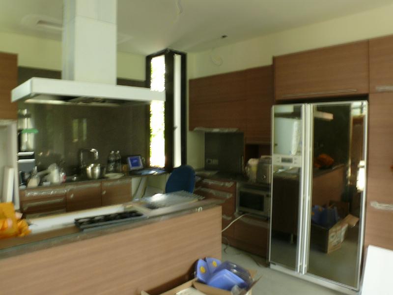 P1000824.JPG - Apologies for the blurry image. I must have accidentally unlocked the camera's exposure override. That mirrored area on the right is our new refrigerator. Jon cleverly identified that it was designed to be used as a "built-in" without the very high prices you typically see for such appliances. The cooktop is awaiting installation of granite on the kitchen island. (Granite has already been installed on the countertops against the far wall and to the left of the refrigerator.)